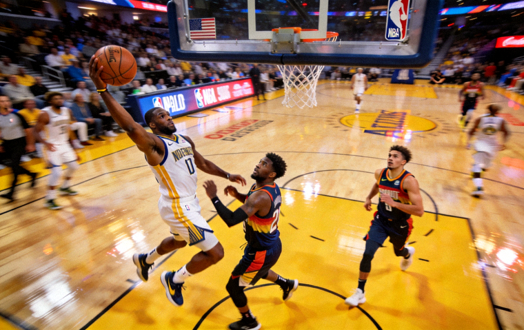 NBA比赛现场，球员在三分线外起跳投篮，篮下有多名球员卡位